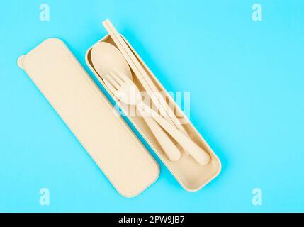Yellow set of plastic spoons, forks and chopsticks kit set on blue background. Stock Photo