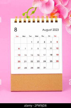August 2023 calendar desk and pink orchid on pink background. Stock Photo