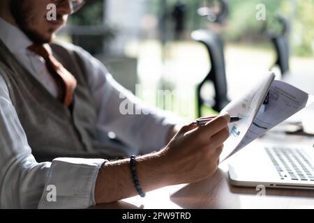 Satisfied man reading paper documents, letters, receiving pleasant news, working at workplace, sitting on desk, successful businessman, freelancer loo Stock Photo