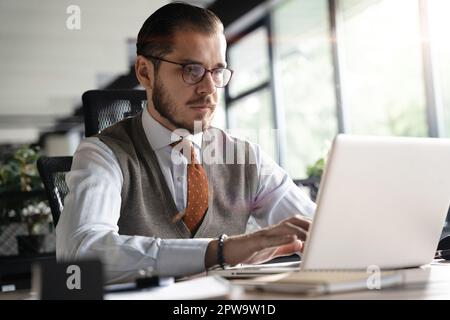 Modern Office Businessman Working on Computer. Portrait of Successful Middle-aged IT Software Engineer Working on a Laptop at his Desk Stock Photo