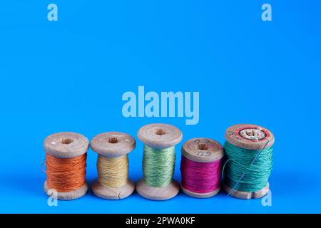 Old wooden reels of thread on blue background Stock Photo