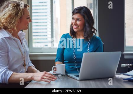 Two working as one. two businesswomen using a laptop together in an office. Stock Photo