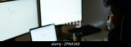 Be busy. Skilled specialist, guy sitting in front of many computer monitors, testing, finishing or debugging software Stock Photo