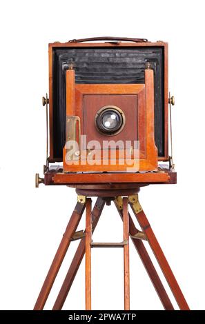 Antique bellows style camera front view close up on an old wooden tripod isolated on white Stock Photo