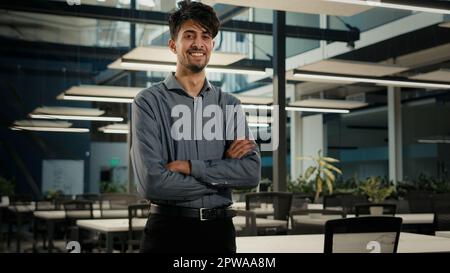 Successful smiling businessman indian arabian man posing in office with arms crossed. Confident male agent company owner executive manager young Stock Photo
