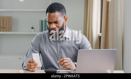 Serious African American ethnic man bookkeeper bearded businessman financial analyst manage business company finance checking budget expenses check Stock Photo