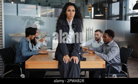Worried upset leader woman tired worker businesswoman sitting on table in conference room sad with business problem failure multicultural team diverse Stock Photo