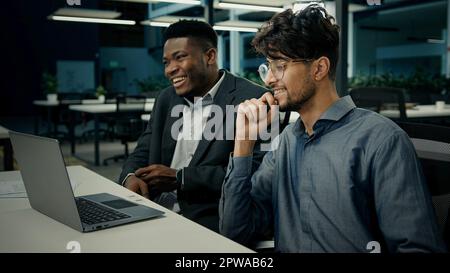 Two businessmen business partners office African American man client talk with Indian businessman colleague diverse ethnic multiracial men laughing Stock Photo