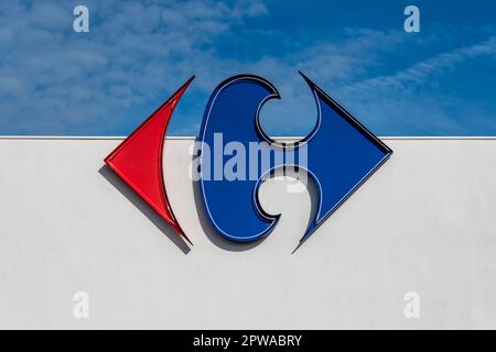 Anglet, France - April 26, 2023: Logo of the Carrefour group on a white wall and blue sky background Stock Photo