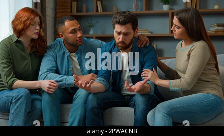 Sad desperate upset caucasian adult 30s man share life problem grief in group therapy session at home diverse people multiracial friends women men Stock Photo