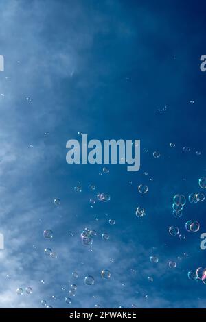 Numerous Colorful Soap Bubbles Float In Mid-Air In Front Of Blue Sky Stock Photo