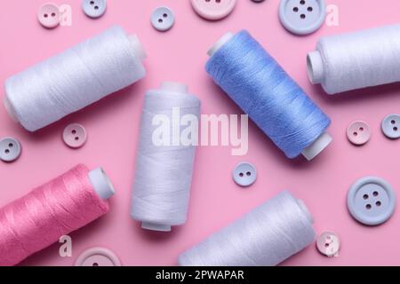 Composition with different thread spools and buttons on pink background, closeup Stock Photo