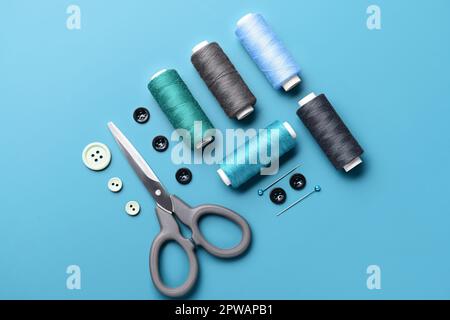 Composition with thread spools, buttons, scissors and ball pins on color background Stock Photo