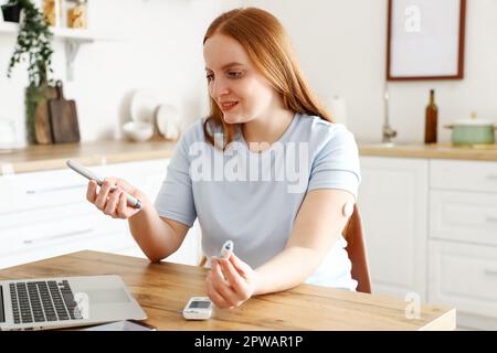 Woman with diabetes measuring blood sugar level at home Stock Photo