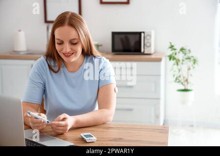 Woman with diabetes measuring blood sugar level at home Stock Photo