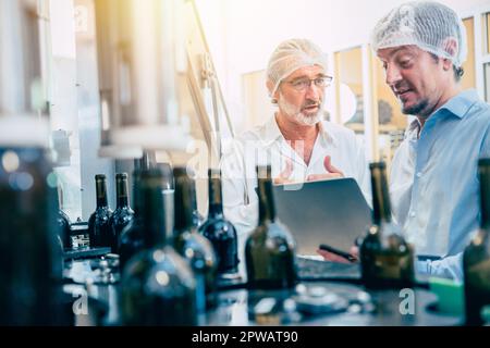 Food production process inspector team working in beverage bottle conveyor line Stock Photo
