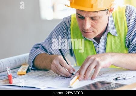 Architect Engineer Builder, Building Designer working with floorplan at Construction Site. Stock Photo
