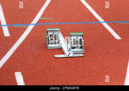 A track sprinters starting blocks set up on a red track. Stock Photo