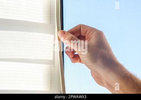 The man wipes the window frame with a degreaser and glues a sealing rubber tape on it for noise insulation, wind protection, weather protection. Stock Photo