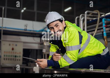 portrait happy engineer factory worker foreman supervisor working in heavy industry sitting relax smiling looking camera. Stock Photo