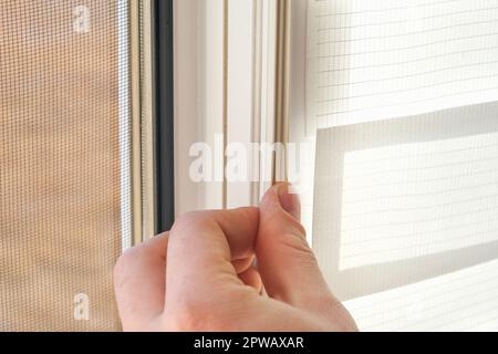 The man wipes the window frame with a degreaser and glues a sealing rubber tape on it for noise insulation, wind protection, weather protection. Stock Photo