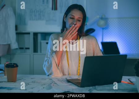 Woman clothing designer hard working overnight at tailor studio Stock Photo