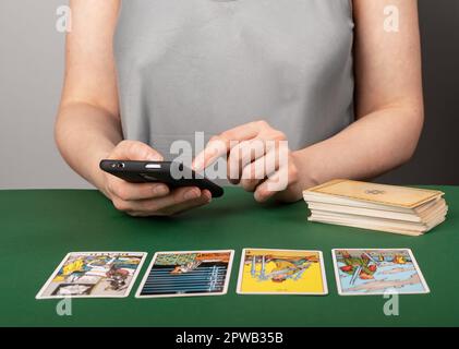 Lodz, Poland March 31 2023 Tarot card reader searching arcana spread meaning online in internet using mobile phone, smartphone, telling, reading taro. Stock Photo