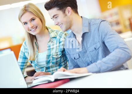 Getting ready for the class test. Two smiling students helping each other with their homework. Stock Photo