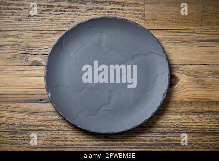 empty black plate on wooden kitchen table, top view Stock Photo