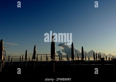 Beach beds with umbrellas on a beach during sunset - ready for the season Stock Photo