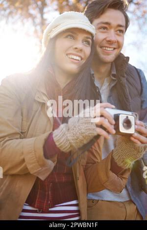 Sunny autumn days are the best. A beautiful young couple enjoying an autumn day together and taking some photos. Stock Photo