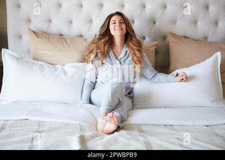 Happiness is the ultimate healer. a beautiful young woman waking up in bed feeling refreshed. Stock Photo