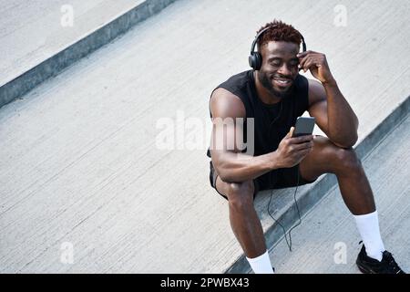 Strong sporty young African man using phone listening music or watching video. Stock Photo