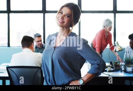 Managers aka the success makers. Portrait of a confident young businesswoman working in a modern office with her colleagues in the background. Stock Photo