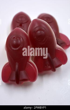 Bright sweet children's jelly candies, interesting rubber sweets in the form of red, cherry space rockets located on a white background. Stock Photo