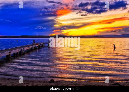 Reflection of setting sun light on surface of Lake macquarie off Murrays beach shore in Australia. Stock Photo