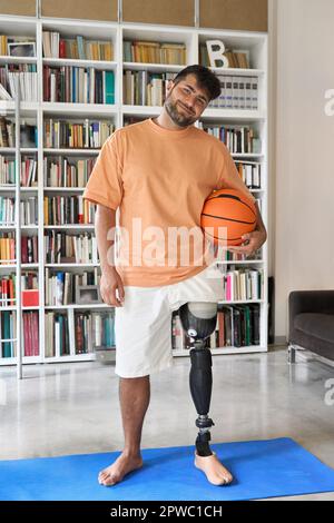 Amputee man with prosthetic leg prosthesis posing with basketball ball. Stock Photo