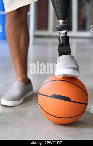 Amputee man with prosthetic leg prosthesis posing with basketball ball. Stock Photo