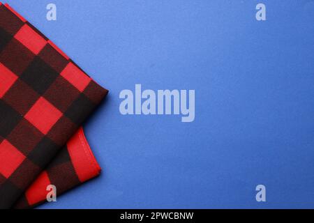 Folded red bandana with check pattern on blue background, top view. Space for text Stock Photo