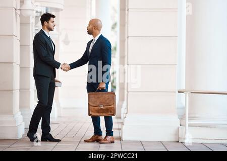 Meeting new businessmen in the city. young handsome businessmen shaking hands outside. Stock Photo
