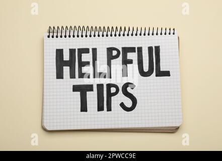 Phrase Helpful Tips in notebook on beige background, top view Stock Photo