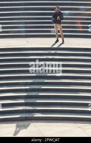 Success is calling him. a young businessman using a mobile phone while walking through the city. Stock Photo