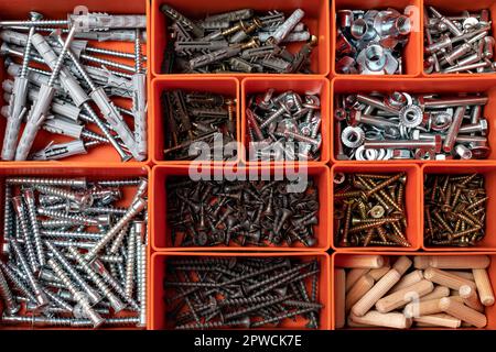 Red tool box with square compartments with screws and dowels Stock Photo