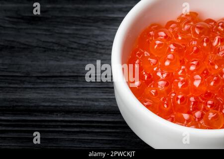 Red caviar in a cup with salt on a wooden background Stock Photo