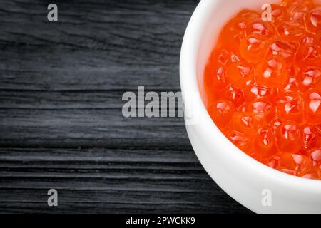 Red caviar in a cup with salt on a wooden background Stock Photo