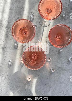 Top view of glasses with cold pink champagne placed on table near cubes of ice during party on summer day Stock Photo