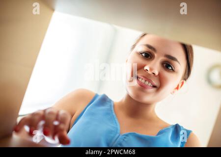 From below happy young female smiling and looking inside carton box while opening ordered goods Stock Photo