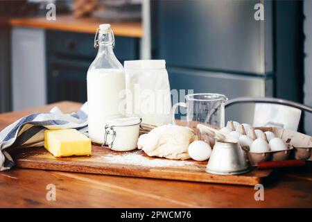 Assorted ingredients for pastry preparation placed on wooden chopping board on table in kitchen Stock Photo