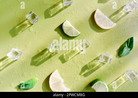 Fresh mint leaf and ice cubes with droplets and lime on green background. Summer background Stock Photo