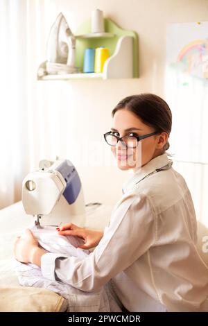 Side view of talented female designer creating garment while working with mannequin in atelier Stock Photo